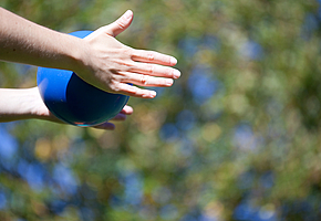 Die Hände einer Frau, welche einen blauen Ball festhält.